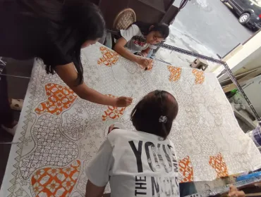 Para perajin batik tengah mewarnai batik Malangan dengan tema 
